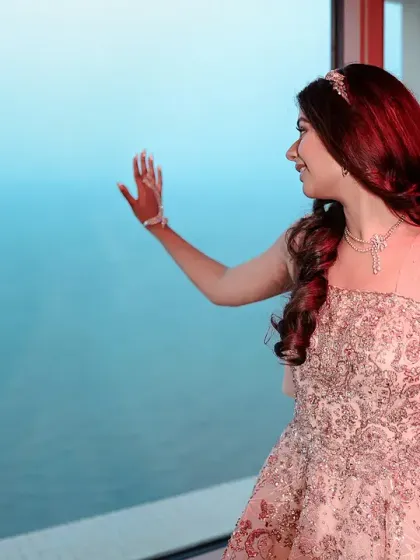 A lovely solo portrait of the bride looking out a window. The soft, natural light from the window and the view of the sea create a serene and contemplative mood.