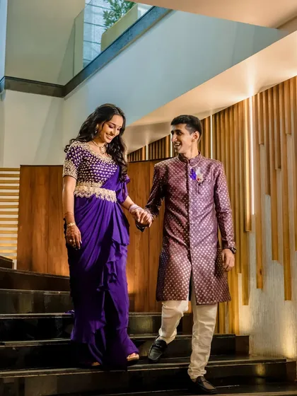 A modern and stylish portrait of a couple on a staircase. The groom leads his bride down the stairs, creating a sense of movement and partnership. The architectural lines add a contemporary feel.