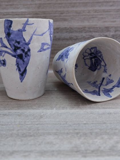 Another view of the hand-painted glasses, showing different floral and bird-like motifs. The beauty is in the imperfection and the free-flowing brushwork.