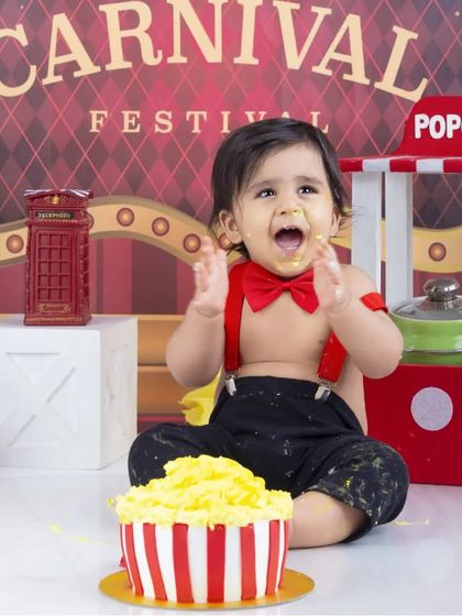 This little ringmaster is enjoying a popcorn-themed cake smash at his carnival festival shoot. A truly unique and playful first birthday idea.
