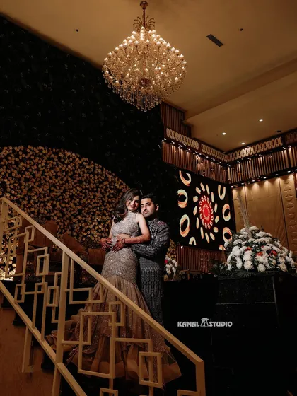 A grand, low-angle shot of the couple on a staircase, capturing the opulence of the venue and the elegance of their attire.