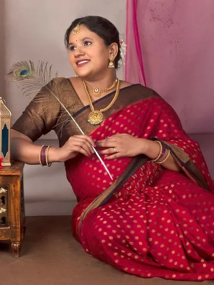 A beautiful portrait of a mama-to-be in a red bandhani saree, seated in a traditional setting.