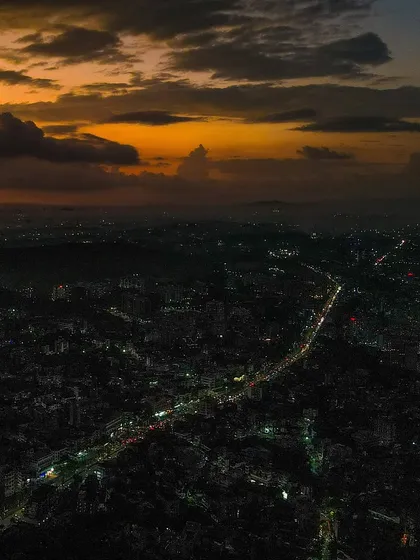 The city lights of Badlapur stretch out towards the horizon under a glowing sunset.