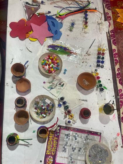 A top-down view of our arts and crafts table, featuring materials for pot painting, foam crafts, and making jewelry with beads and feathers.