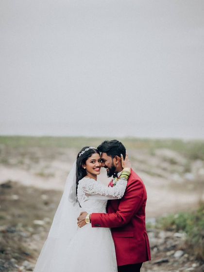 A beautiful portrait of the couple on a beach, with the bride looking at the camera. The contrast between her white dress and his red jacket is striking.
