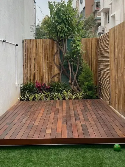 A close-up of a premium Brazilian Ipe wood deck set against a natural bamboo fence. Ipe wood is known for its incredible durability and rich color, making it a fantastic long-term investment for a luxurious and low-maintenance outdoor floor.