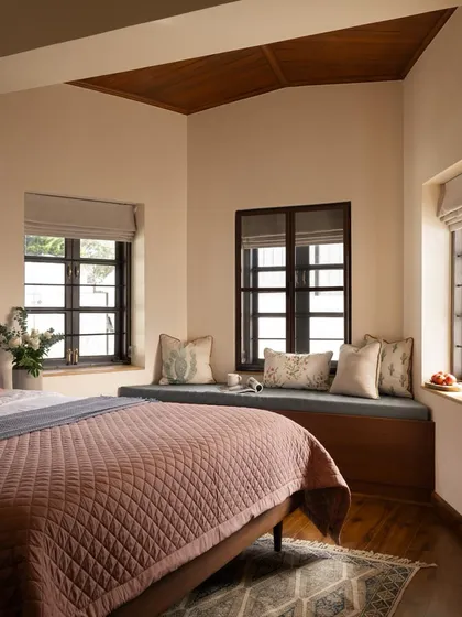 A cozy bedroom in the Coonoor villa, complete with a built-in window seat that offers a perfect spot for reading while enjoying views of the Nilgiri hills.