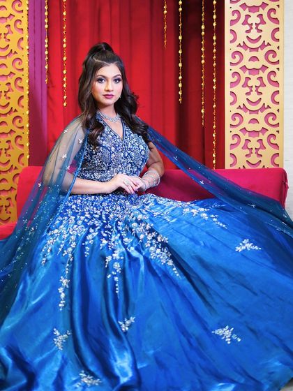 A seated portrait showing the volume and richness of the blue gown.