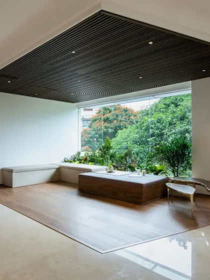 This sunken lounge area is designed to bring the outdoors in. A large picture window frames the lush greenery outside, while the built-in seating and low coffee table create an intimate space for relaxation and contemplation.