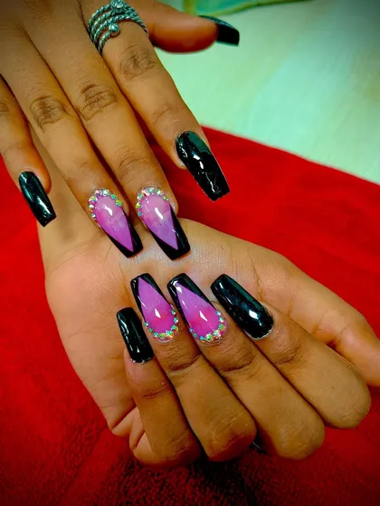 A dramatic look combining glossy black coffin nails with accent nails that have a pink-to-black ombre V-French design, outlined with sparkling rhinestones.