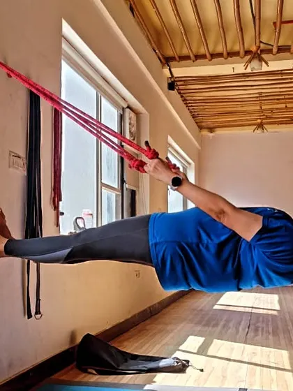 This student holds a perfect horizontal plank using the wall ropes. This asana builds immense core and upper body strength and requires intense focus and control.