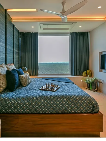 This bedroom is designed to maximize the stunning sea view, with a large window framing the horizon. The color palette of blues and browns echoes the natural landscape outside.