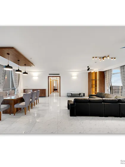 This photograph captures an open-plan living and dining area, defined by its clean lines and minimalist luxury. The spacious layout, with its marble flooring and expansive windows, creates a bright and sophisticated environment, perfect for modern living.