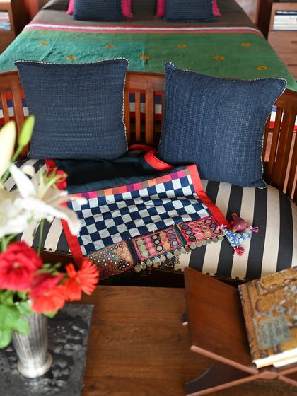 The throw styled with coordinating cushions, demonstrating how to create a cohesive look. The deep indigo of the linen pairs beautifully with the colorful embroidery.