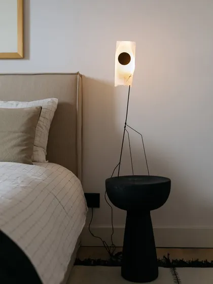 The bedside detail in the Corner House features a slender, ambient table lamp by Ann Demeulemeester. Its delicate form is contrasted with a dark, solid bedside table, highlighting our focus on curating unique design objects.