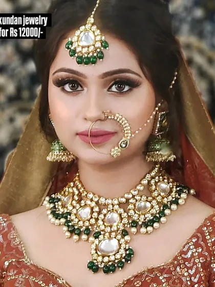 A beautiful Kundan jewellery set with a large maang tikka and jhumkas, featuring green and white stones. This complete set is available for purchase.