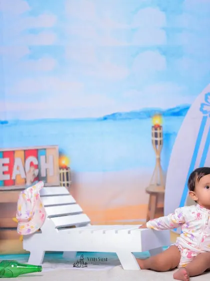 A wide shot showing the full beach setup. The colorful props and bright lighting create a joyful atmosphere for this baby girl's photoshoot.
