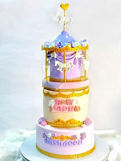 A grand three-tier carousel cake to celebrate two sisters' birthdays together. The pastel purple and pink colors and golden details give it a whimsical, regal feel.