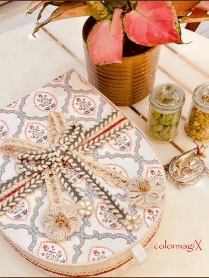 The exterior of our teardrop-shaped box, featuring a beautiful traditional print and an intricate woven ribbon. This is packaging that is designed to be treasured.