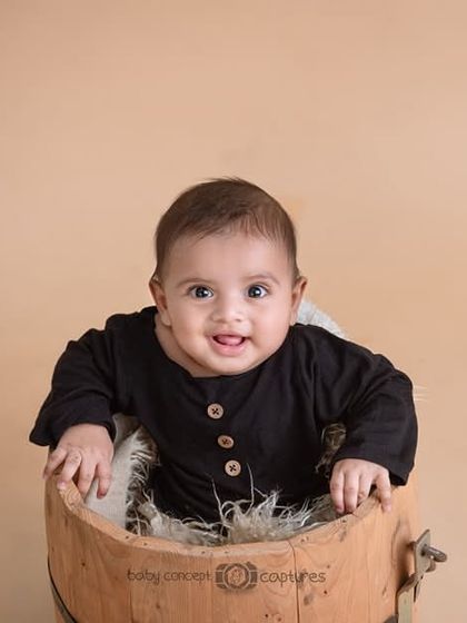 A simple and classic portrait of a baby in a wooden bucket. This timeless style is perfect for capturing your baby at any age, focusing on their happy expression.