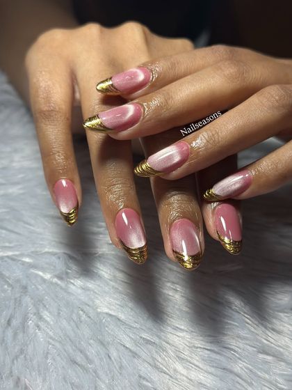 A glamorous set featuring a pink cat eye base with sculpted gold chrome on the tips. This is a bold and luxurious look.