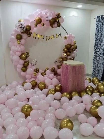 A close-up of the circular arch and cake table in the pink and gold balloon-filled room.