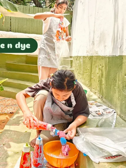 A child applies dye to a t-shirt as part of a tie-dye project for an animal welfare fundraiser. This messy, creative work was a joyful way for the children to contribute to their community.