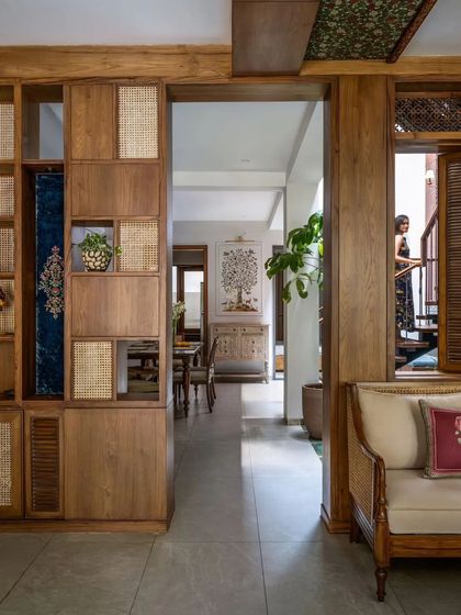 A custom-designed shelving unit combines wood and cane, providing storage while also acting as a beautiful partition between spaces.