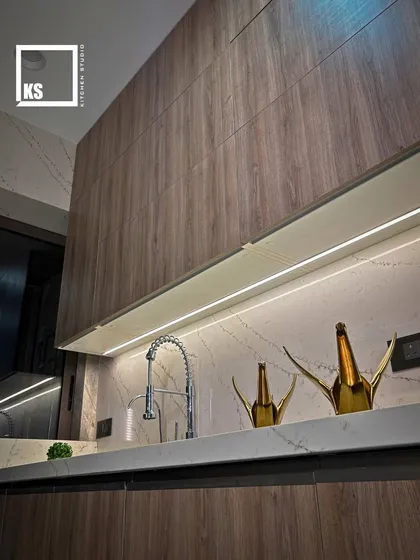We combined warm wood-laminate cabinets with a white marble-patterned quartz. The under-cabinet lighting highlights the beautiful texture of the backsplash and provides functional light for the workspace.