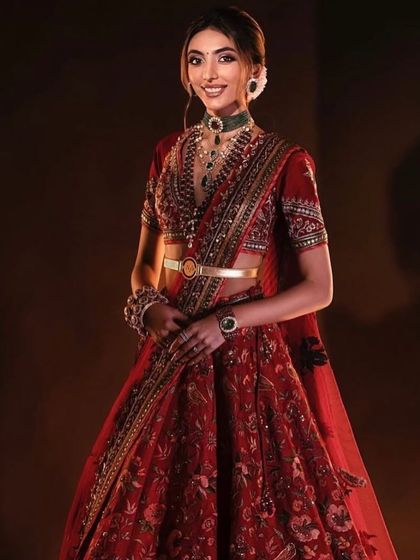 A full-length view of the regal red bridal look. The makeup and styling come together to create a powerful and timeless image of a bride on her special day.