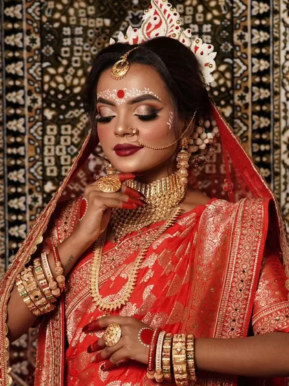 A graceful pose by the Bengali bride, showcasing her complete traditional attire and gold-look jewellery set.