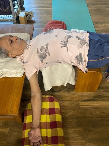 A supported bridge pose using a bench and belts. This therapeutic variation helps to align the pelvis and release tension in the lower back.