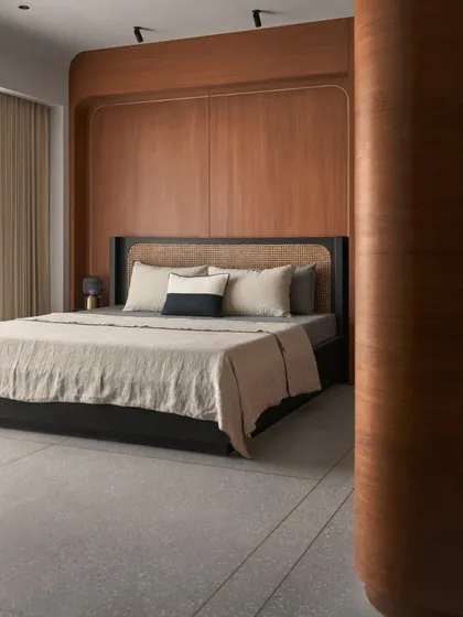 This bedroom showcases a retro 80s influence within a Japandi framework. The custom black bed with a rattan headboard is set against a warm wood-panelled wall, creating a cozy and stylish personal retreat.