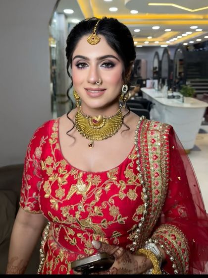 A beautiful smile from this bride in her red and gold outfit. Her makeup features a soft purple and brown eyeshadow blend, a sharp wing, and a natural skin finish, perfect for her morning wedding.