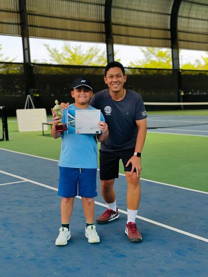 A young champion receives his trophy and certificate from our coach after a successful tournament run. One-on-one encouragement is a key part of our coaching philosophy.