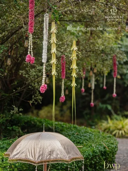 Blending decor into nature. We used hanging floral arrangements and coconut leaf tassels to adorn the trees, adding a touch of traditional elegance to the outdoor space.