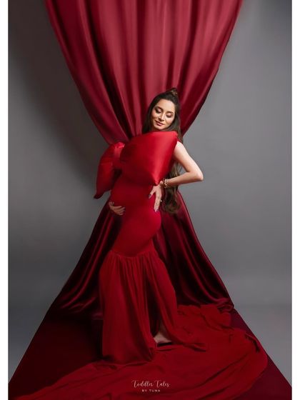 A vision in red. This portrait showcases a unique, structured red gown against a simple backdrop, letting the architectural details and the mother's elegant pose take center stage.