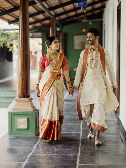 A couple walks hand-in-hand down a heritage corridor, sharing a look of love and happiness.