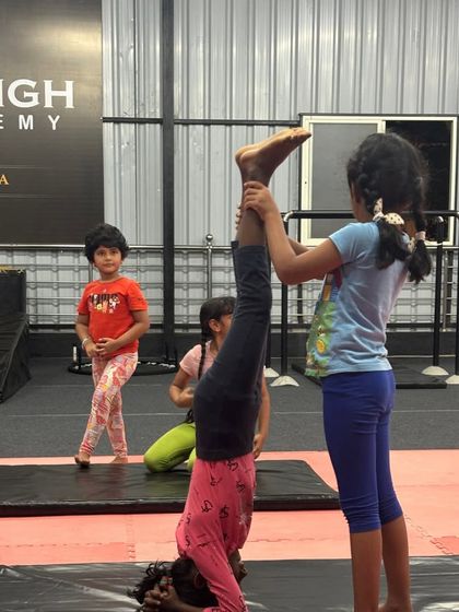 Teamwork makes the dream work. Here, one student helps another stabilize her headstand, fostering a sense of community.