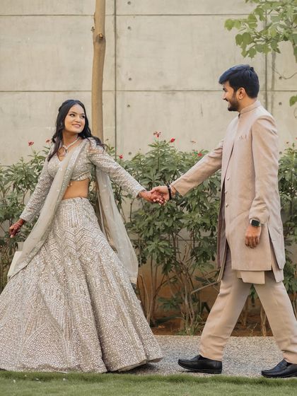 Walking towards their forever. The bride looks graceful in her silver lehenga, with a simple yet beautiful hairstyle and makeup that enhances her happy glow.