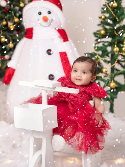 A little princess in a beautiful red dress, enjoying a magical snowfall in our winter wonderland setup.