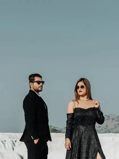 A stylish, modern portrait of a couple in a stark white landscape. Their chic black outfits create a beautiful contrast against the bright background.