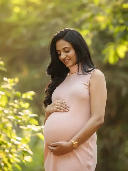 A beautiful solo portrait, cradling your bump in the soft sunlight. You look so peaceful and radiant in this natural setting.