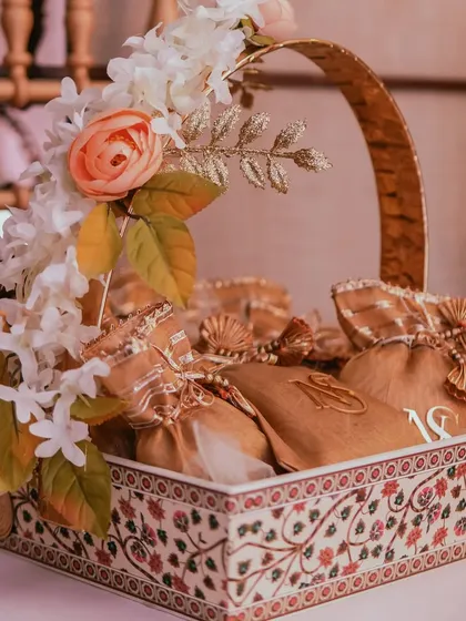 An elegant gift basket for a Roka ceremony, filled with personalized pouches. The intricate design of the basket and the custom monograms add a touch of traditional luxury.