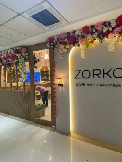 An elegant artificial floral installation framing the entrance of Zorko Cafe. This type of long-lasting decor is perfect for creating a sophisticated first impression for cafes, salons, and boutiques.