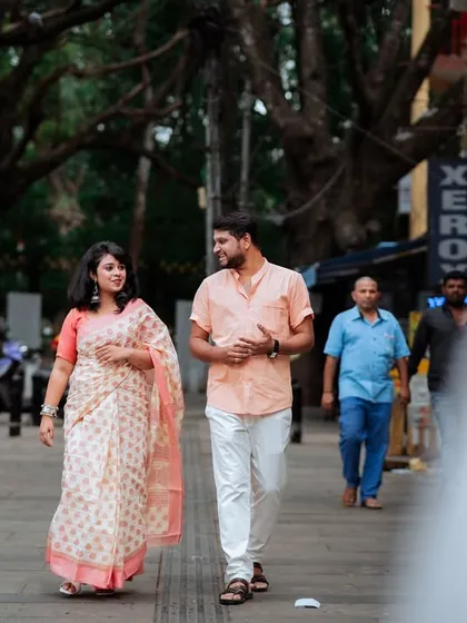 A wider perspective of the couple's stroll, showing the hustle and bustle of the city around them. This documentary-style shot freezes a private moment in a public space, making it feel intimate and real.