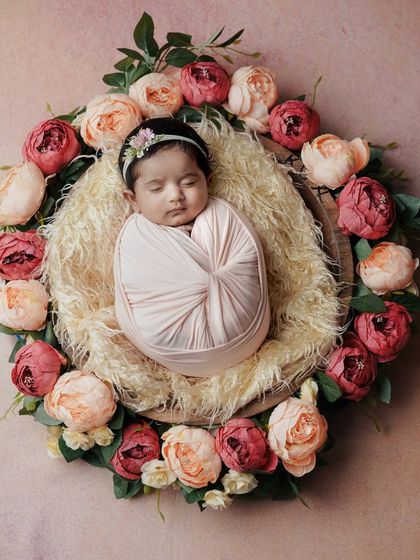 A perfect little blossom. This classic swaddle pose, with the baby wrapped tightly and placed in a nest of flowers, is a beautiful way to capture their tiny form.