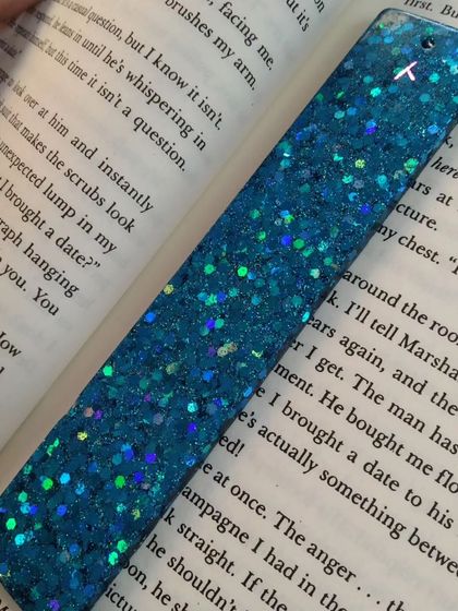 A bookmark filled with chunky, holographic blue glitter. This piece is perfect for anyone who loves a bit of sparkle in their reading.