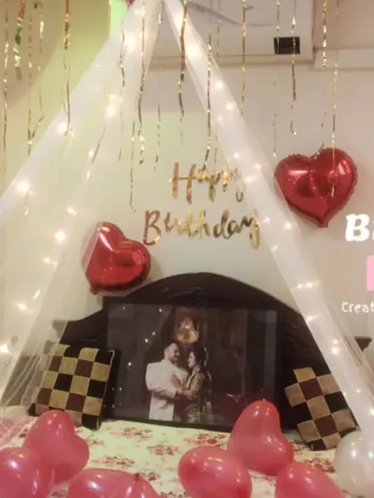 A simple yet beautiful birthday surprise. This setup features a delicate canopy over the bed illuminated with fairy lights, heart-shaped balloons, and a framed photo to add a personal touch.