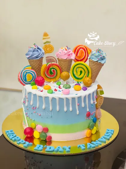 A candy-loaded drip cake for a kid's birthday. This colorful creation is topped with lollipops, ice cream cones, and lots of candy.
